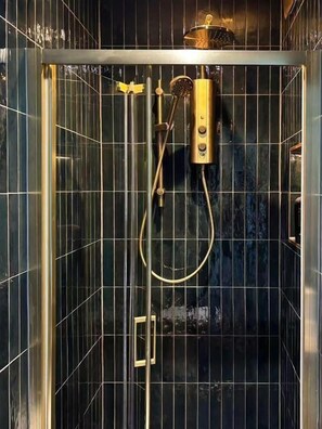 A shower enclosure with a glass door, a handheld showerhead, and a wall-mounted control panel. - Angel en-suite rooms (London)