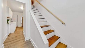 A staircase with wooden steps and white walls, leading to a room with a kitchen area visible in the background. - Jungle House Luxury Homes - Columbus Downtown Short North - Near Convention Center & Nationwide Arena - Free Parking - Pet Friendly - Over 5,800 Five Stars (Columbus)