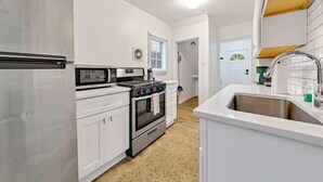 A kitchen with white cabinets, a stainless steel sink, and a stove. - Jungle House Luxury Homes - Columbus Downtown Short North - Near Convention Center & Nationwide Arena - Free Parking - Pet Friendly - Over 5,800 Five Stars (Columbus)