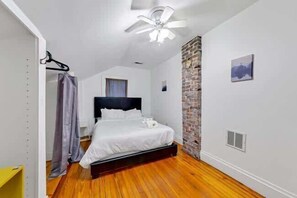 Ein Schlafzimmer mit Bett, Deckenventilator, Ziegelfassade und Fenster.