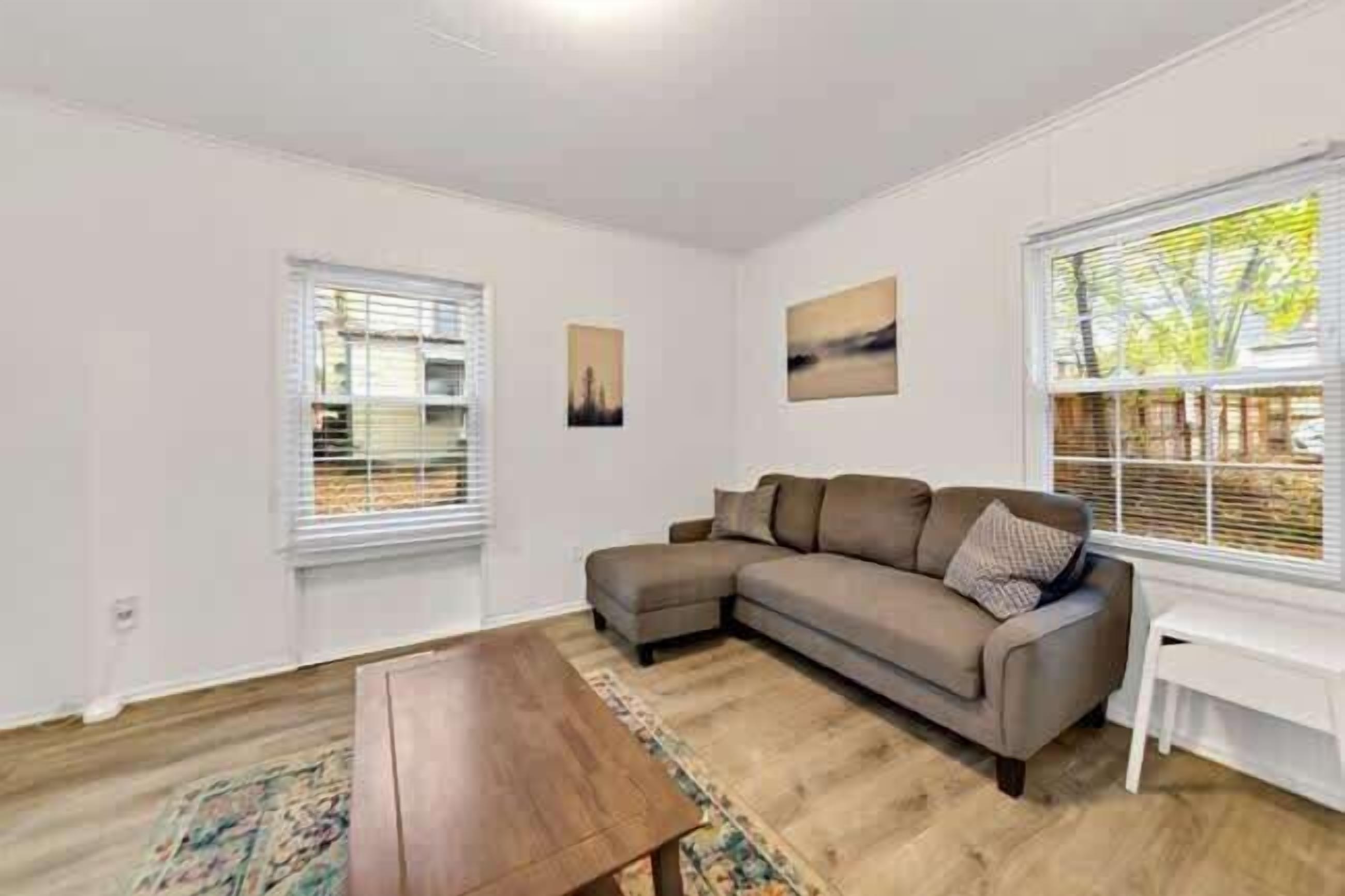 A living room with a sectional sofa, a coffee table, and a window with blinds.