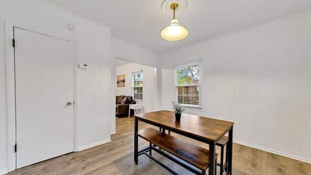 A room with a wooden floor, a white door, a dining table with benches, and a hanging light fixture. - Jungle House Luxury Homes - Columbus Downtown Short North - Near Convention Center & Nationwide Arena - Free Parking - Pet Friendly - Over 5,800 Five Stars (Columbus)
