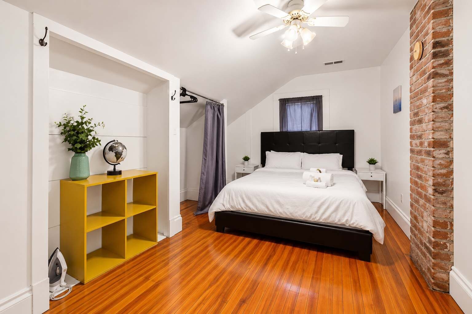 Une chambre à coucher avec un lit, une étagère jaune, un globe terrestre et un ventilateur de plafond.