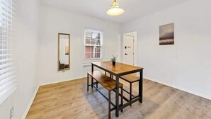 A room with a wooden dining table, benches, a hanging light fixture, a window with blinds, and a framed picture on the wall. - Jungle House Luxury Homes - Columbus Downtown Short North - Near Convention Center & Nationwide Arena - Free Parking - Pet Friendly - Over 5,800 Five Stars (Columbus)