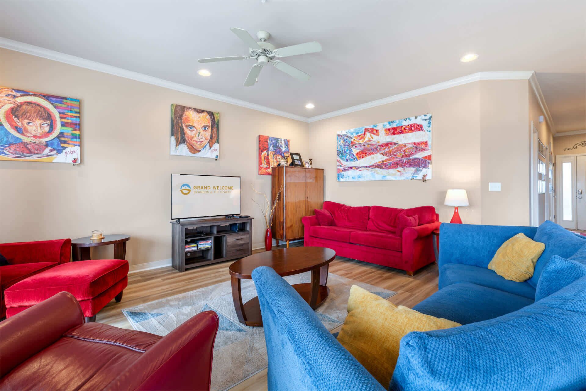 A living room with red and blue sofas, a coffee table, and artwork on the walls.