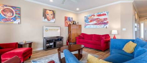 A living room with red and blue sofas, a coffee table, and artwork on the walls.