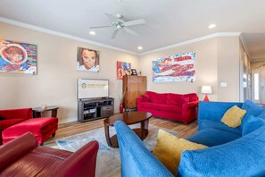 A living room with red and blue sofas, a coffee table, and artwork on the walls.