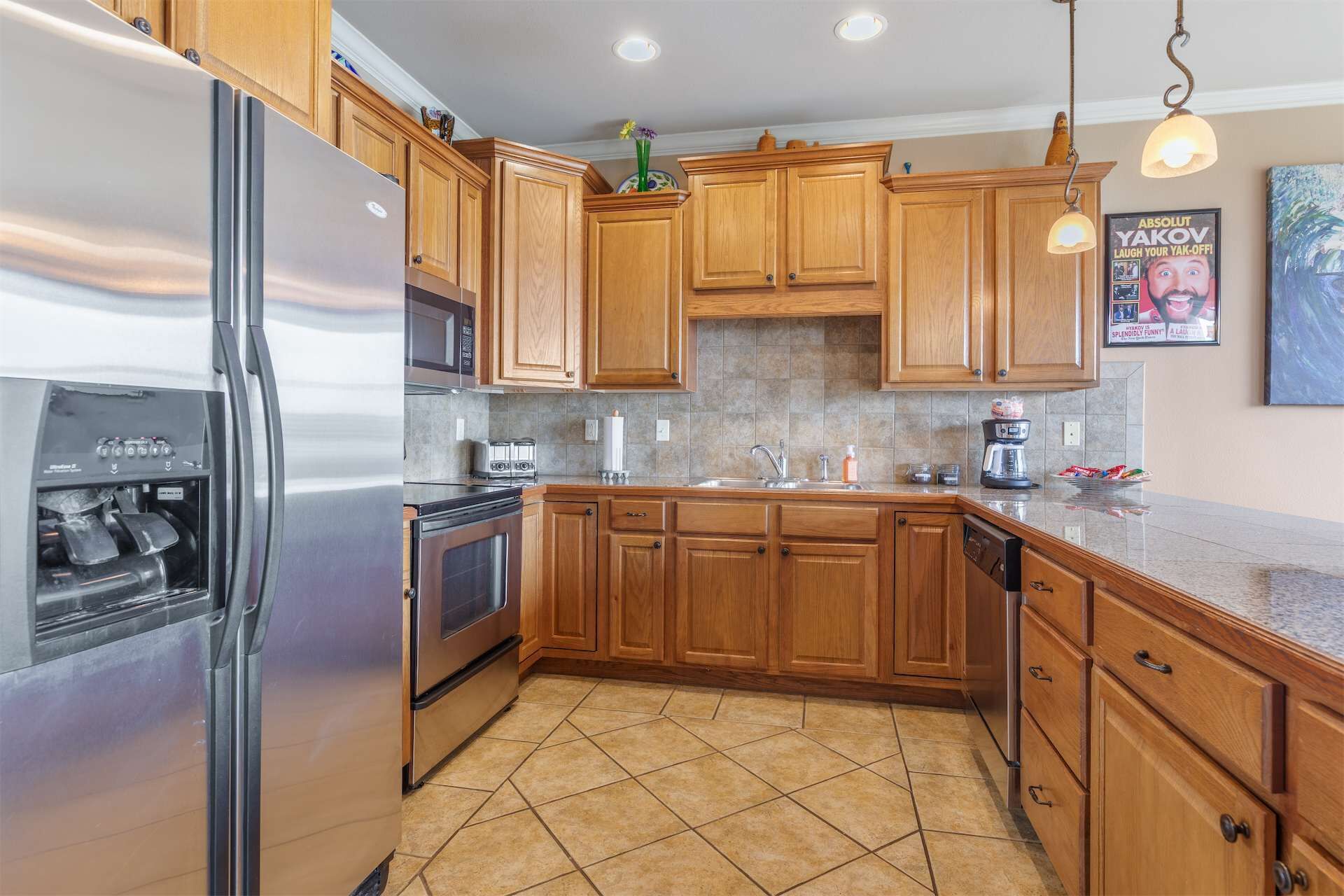 A kitchen with wooden cabinets, stainless steel appliances, and a tiled floor.