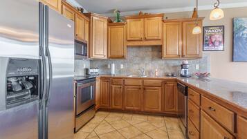 A kitchen with wooden cabinets, stainless steel appliances, and a tiled floor.