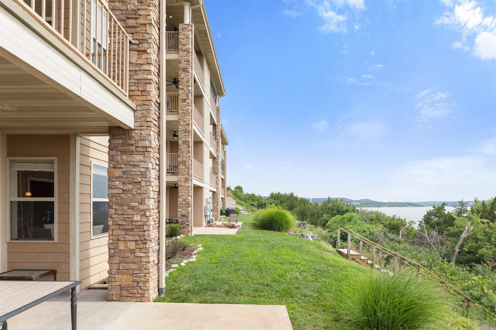 A multi-story building with a stone facade, a covered outdoor area, and a view of a body of water.