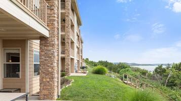 A multi-story building with a stone facade, a covered outdoor area, and a view of a body of water.