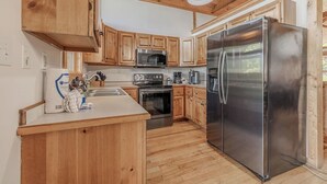 Una cocina moderna con armarios de madera, electrodomésticos de acero inoxidable y una isla central.