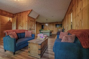 A cozy room with wooden walls, a pool table, and two sofas with blankets. - Family Retreat | Mountain View | Great Location (Sevierville)