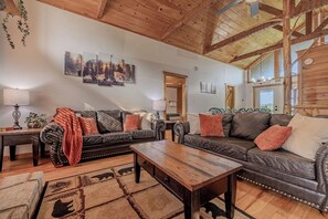 A cozy living room with a wooden ceiling, leather sofas, a coffee table, and a rug with animal prints. - Family Retreat | Mountain View | Great Location (Sevierville)