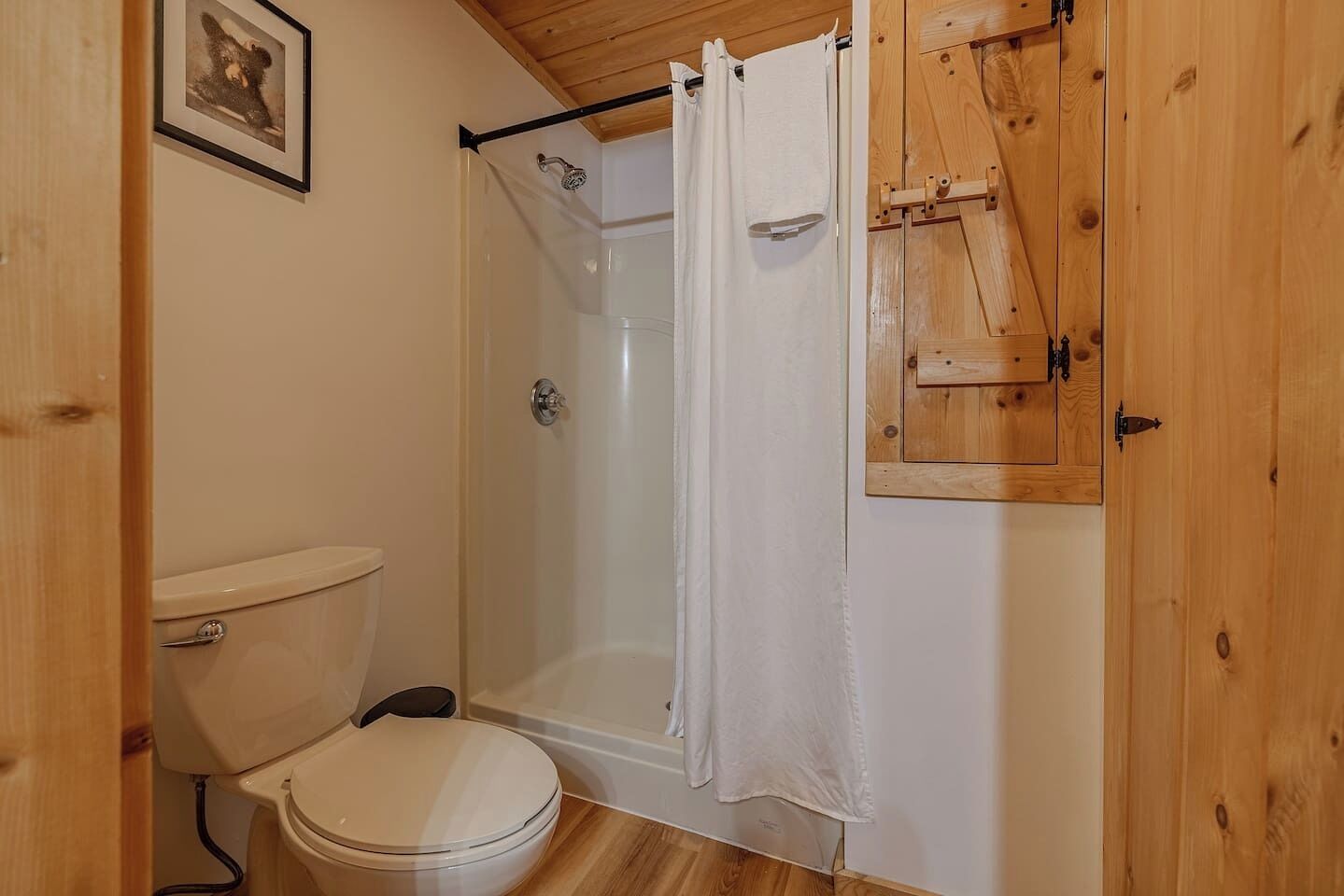 A bathroom with a toilet, a shower enclosure, and wooden cabinetry.