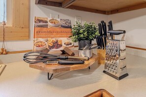 Eine Küchenarbeitsplatte mit Schneidebrett, Reibe und einer Topfpflanze.