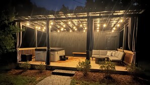 A covered outdoor seating area with a wooden pergola, cushioned seating, and string lights. - 3 Bedroom Private Lakefront Retreat with Pool, Dock, and Hot Tub (Decatur)