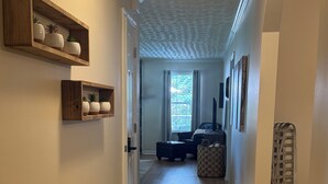 A hallway with wooden floors, a rug, and shelves with potted plants. - 3 Bedroom Private Lakefront Retreat with Pool, Dock, and Hot Tub (Decatur)