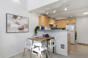 A modern kitchen with a wooden island, white chairs, and a framed abstract painting on the wall. - Downtown Seattle Loft with Rooftop & Skyline Views (Seattle)