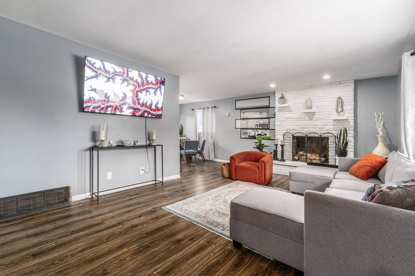 Ein modernes Wohnzimmer mit Flachbildfernseher, grauen Sofas, einem Kamin und Holzboden.