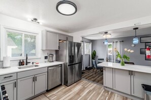 Une cuisine moderne équipée d’appareils électroménagers en acier inoxydable, d’un lave-vaisselle et d’un coin repas avec une table et des chaises.