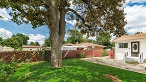A residential property with a well-maintained lawn, a large tree, and a two-story house with a visible garage.