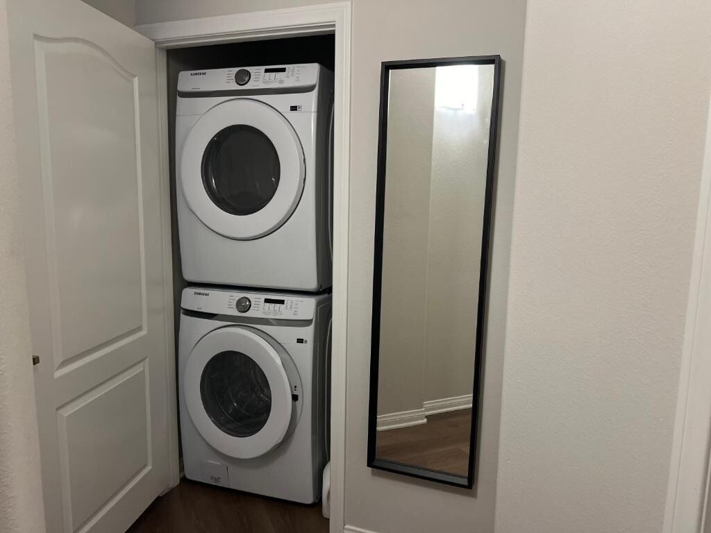 A laundry room with two stacked washing machines and a mirror on the wall.