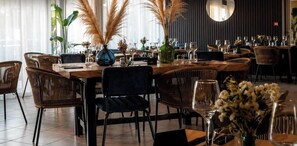 Ein Restaurantinnenraum mit runden Tischen, Korbstühlen und dekorativen Vasen.