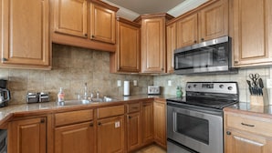A kitchen with wooden cabinets, stainless steel appliances, a microwave, a toaster, and a sink. - Yakov's Pointe - Pool Access (Hollister)