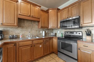 Una cocina con armarios de madera, electrodomésticos de acero inoxidable, un microondas, un tostador y un lavabo.