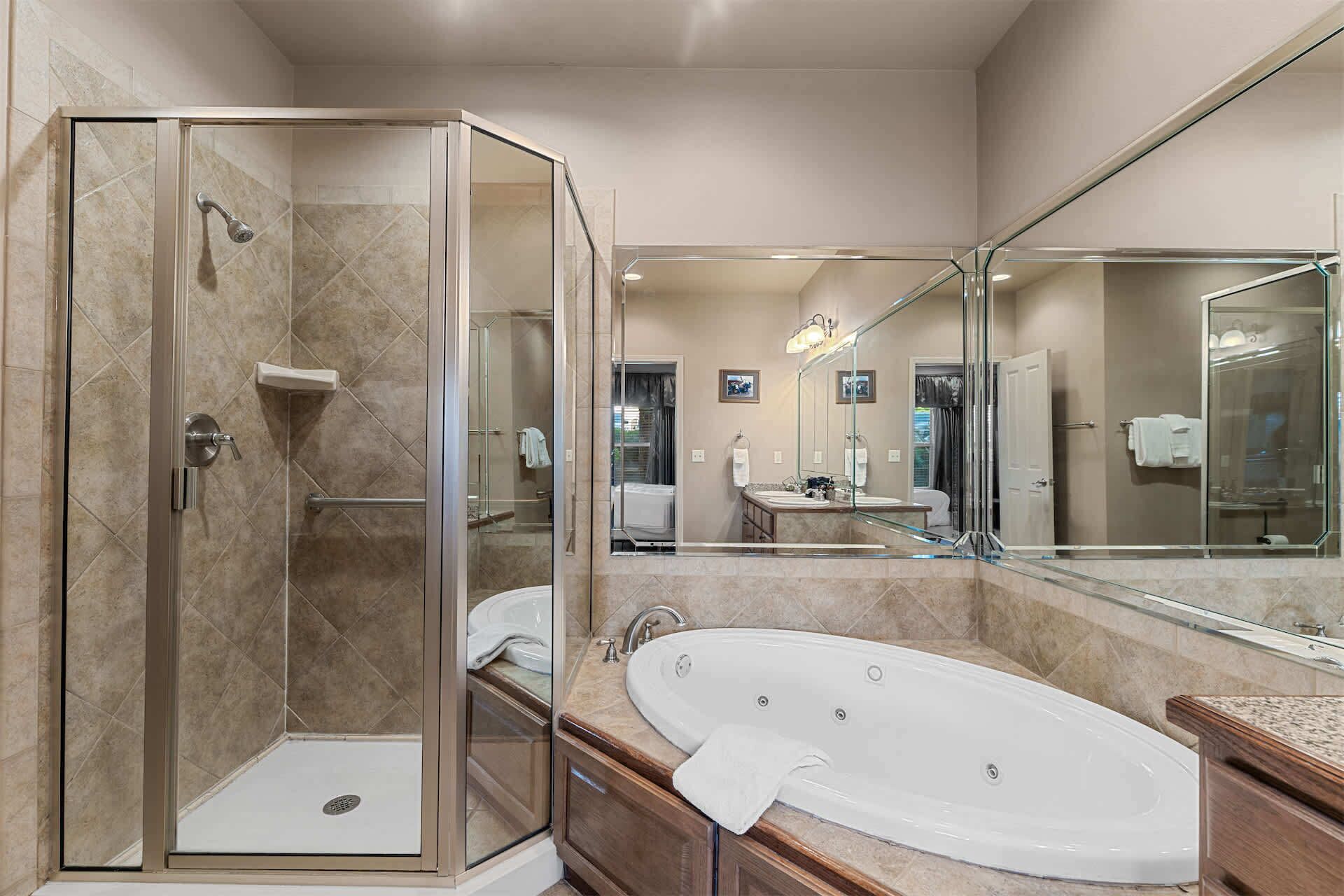 A modern bathroom with a glass-enclosed shower, a freestanding bathtub, and a large mirror reflecting the room.