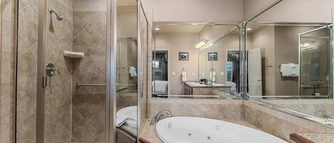 A modern bathroom with a glass-enclosed shower, a freestanding bathtub, and a large mirror reflecting the room.