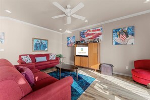 A living room with a red sofa, a coffee table, and a TV screen displaying 'GRAND WELCOME BRANSON & THE OZARKS'. - Yakov's Pointe - Pool Access (Hollister)