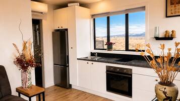 A modern kitchen with a view of a desert landscape, white cabinetry, and a black countertop.