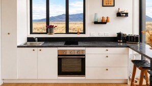 A kitchen with a large window, a built-in oven, and a countertop with various items.