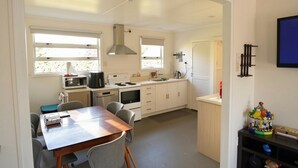 A compact kitchen with a dining area, a microwave, a kettle, and a stove. - Fabulous Family Stay (Twizel)