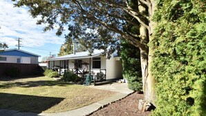 A residential property with a covered porch, a lawn, and a large tree. - Fabulous Family Stay (Twizel)