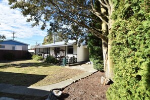 A residential property with a covered porch, a lawn, and a large tree. - Fabulous Family Stay (Twizel)
