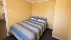 A single bed with a striped bedspread in a room with yellow walls and a carpeted floor. - Fabulous Family Stay (Twizel)