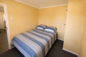 A single bed with a striped bedspread in a room with yellow walls and a carpeted floor. - Fabulous Family Stay (Twizel)
