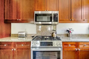 A kitchen with wooden cabinets, a stainless steel microwave, a gas stove, and an oven. - Luxury-Remodeled-Pools-Patios, Ground Floor-3 BD 2BA 12 Pools Jacuzzi Views (La Quinta)