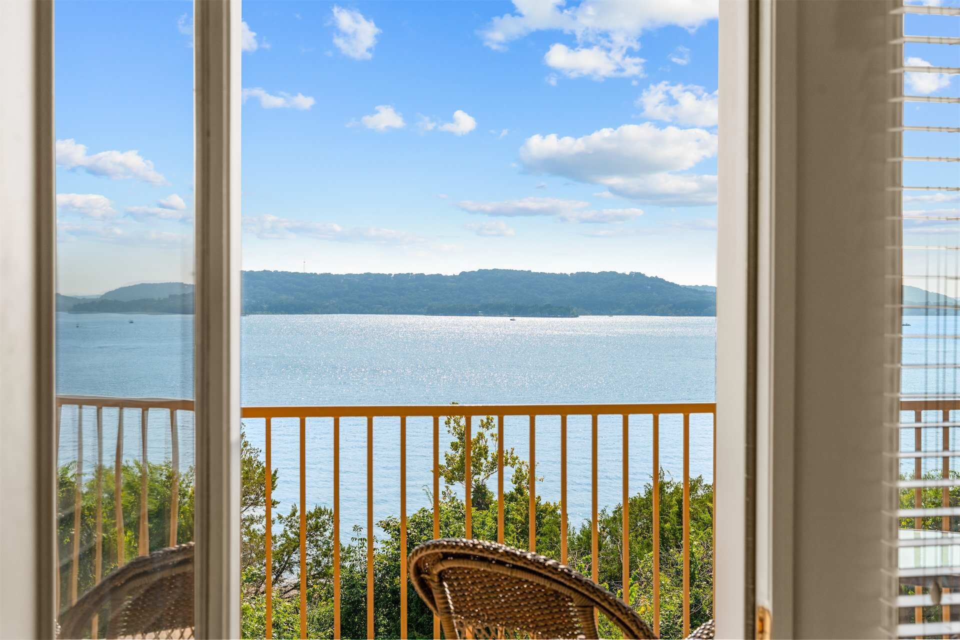 A balcony with a view of a calm body of water and distant hills.