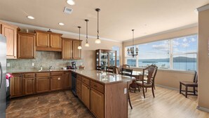 A kitchen with wooden cabinets, a granite countertop, and a dining area with a view of the water. - Smirnoff Pointe - Lakefront (Hollister)