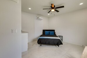 Ein Schlafzimmer mit einem Bett, einem Deckenventilator, einer Klimaanlage und einem kleinen Nachttisch.