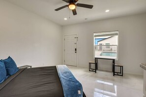 Ein Schlafzimmer mit einem Bett, einem Deckenventilator, einem Fenster mit Blick auf einen Pool und einer Tür.