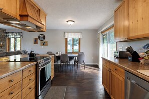 A kitchen with wooden cabinets, a built-in oven, a dining table with chairs, and a window providing natural light.