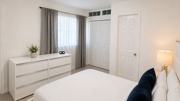 A bedroom with a bed, a dresser, a door, and a window with curtains. - Cozy 1-bedroom apartment in  Fort Lauderdale, two blocks from the beach (Fort Lauderdale)