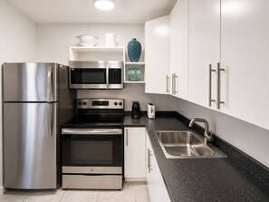 A modern kitchen with stainless steel appliances, including a refrigerator, microwave, oven, and toaster. - Cozy 1-bedroom apartment in  Fort Lauderdale, two blocks from the beach (Fort Lauderdale)