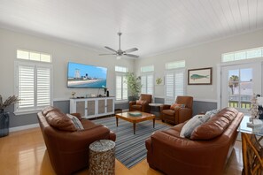 A spacious living room with leather sofas, a coffee table, and a television displaying a cityscape. - Canary by the Sea | Sunny Beachside Escape • Private Pool • 2 Min Walk to Beach (South Padre Island)