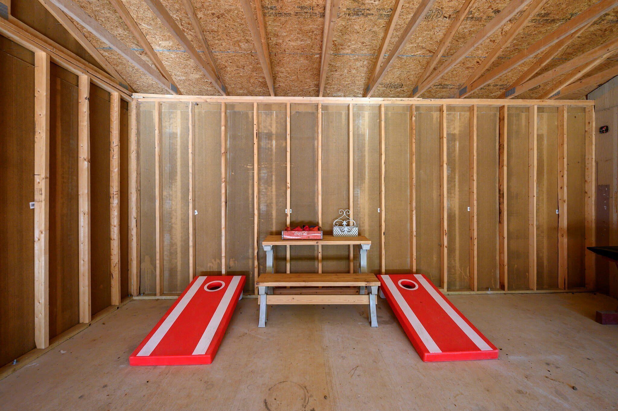 A room with wooden walls and a central table with a red and white design, two benches, and a Coca-Cola cooler.